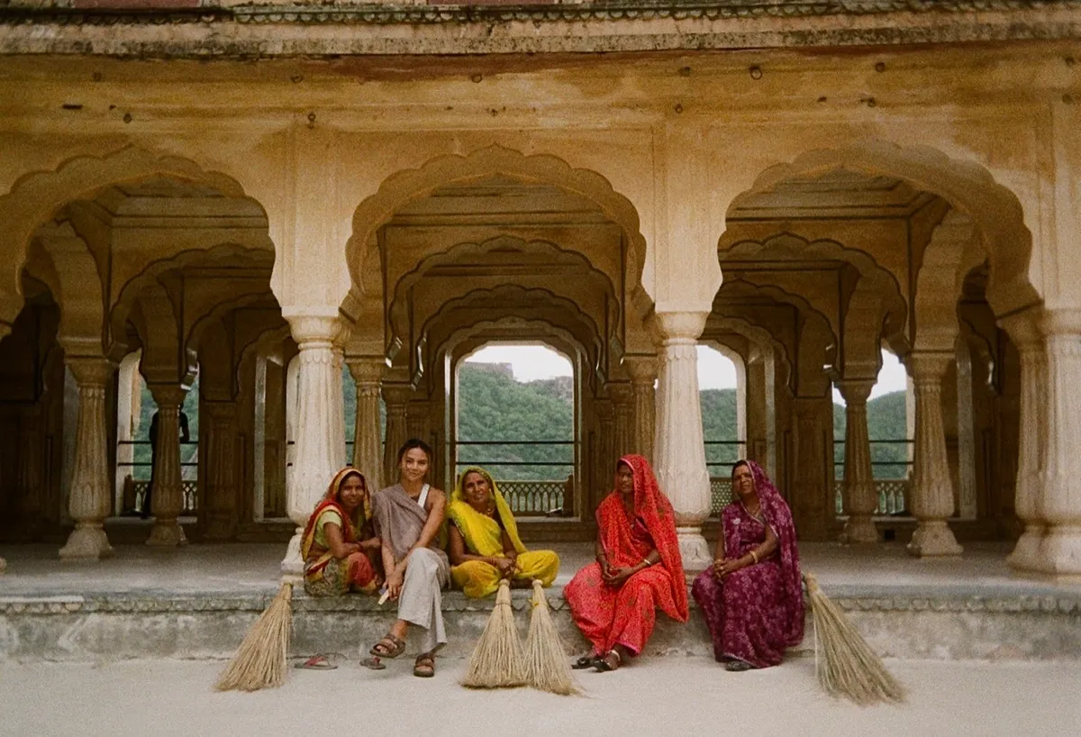 Jidienne sitting with a group of women under carved stone arches